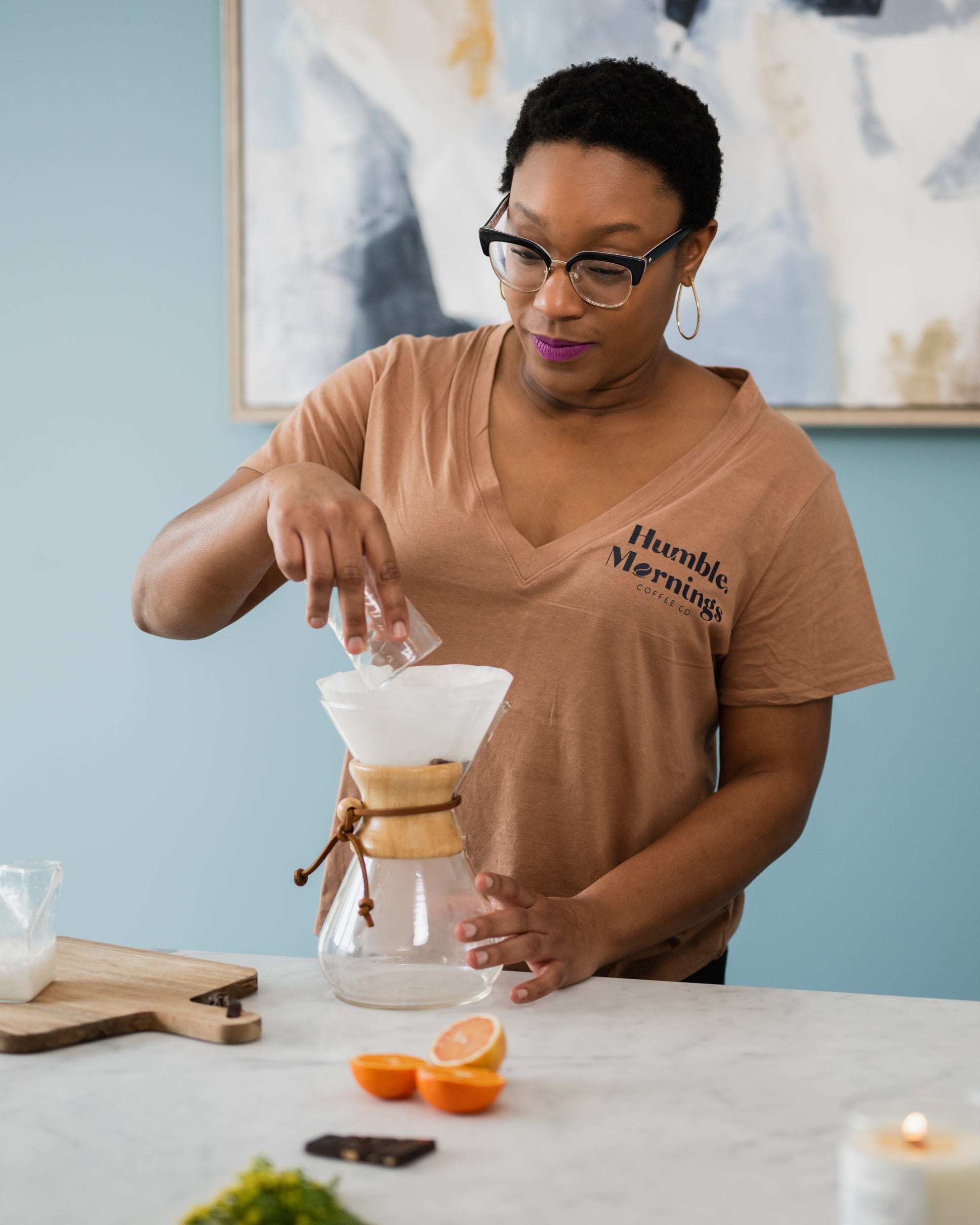 A woman pouring coffee into a coffee mug from a glass coffee maker.